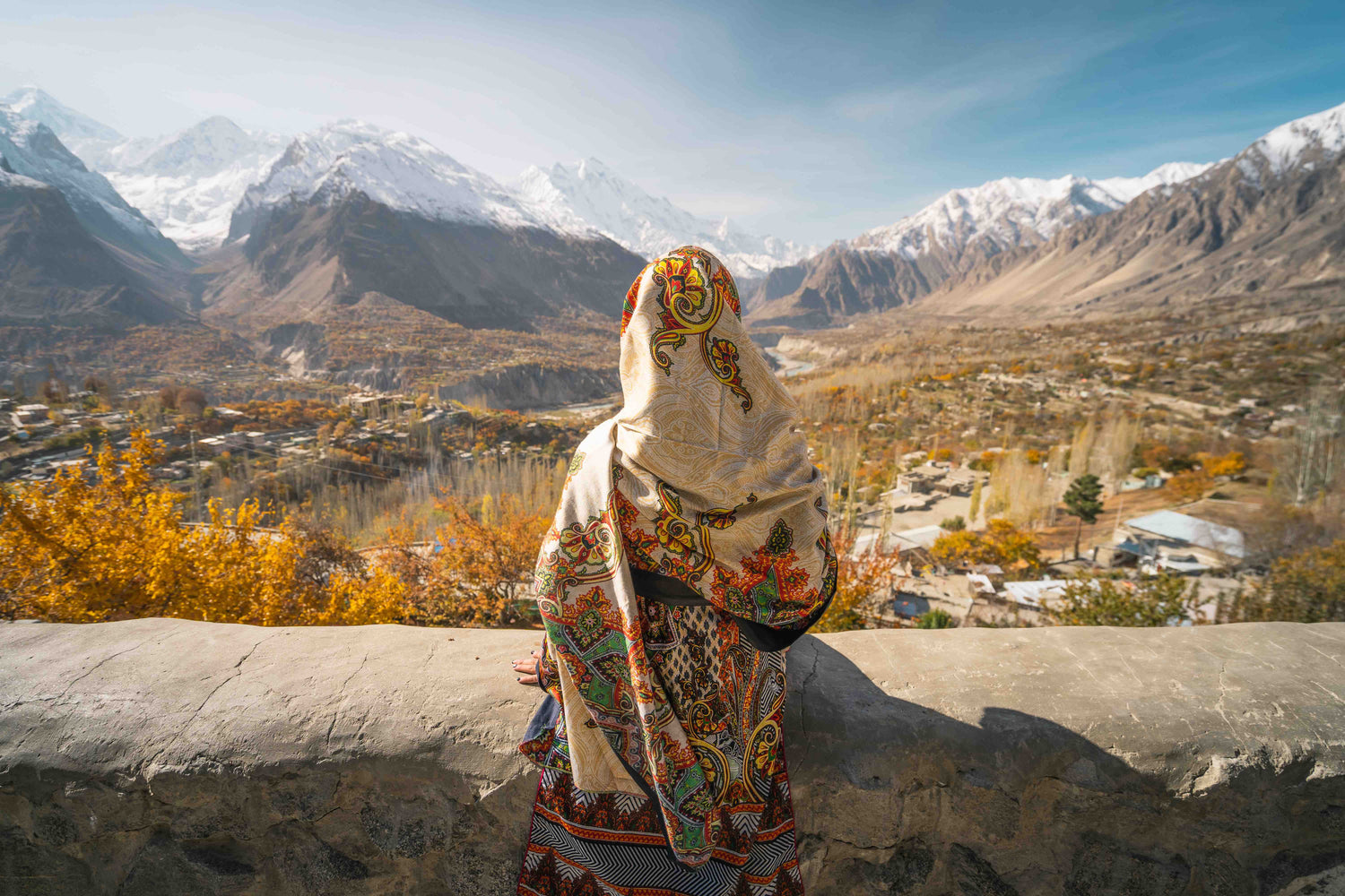 A Pakistani woman looking out over snow-capped mountains.