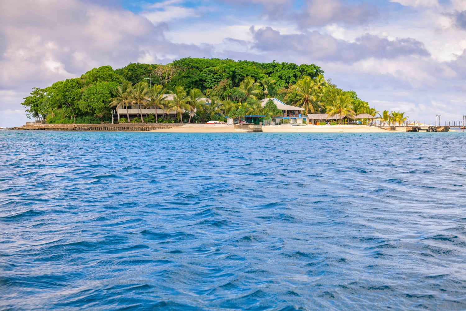 Mele Island, Vanuatu, with lush greenery and resort surrounded by blue water and cloudy sky