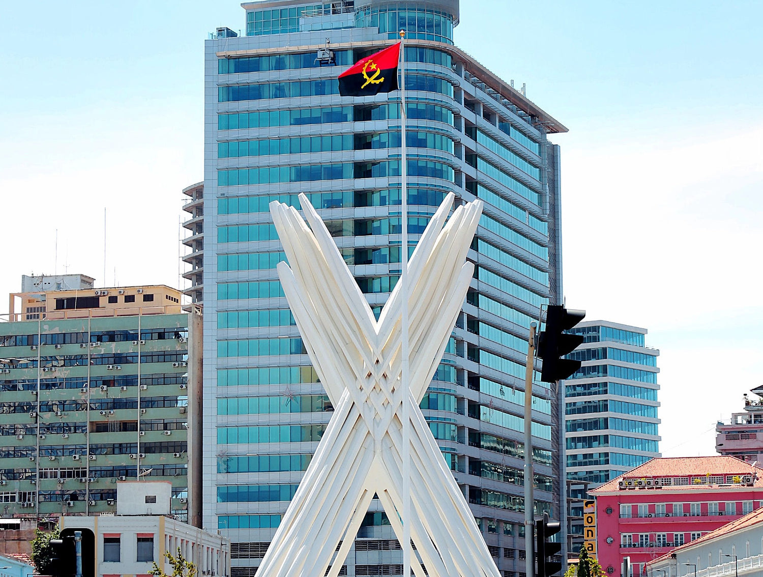 Modern cityscape in Angola with a tall building and a distinctive white sculpture in the foreground.