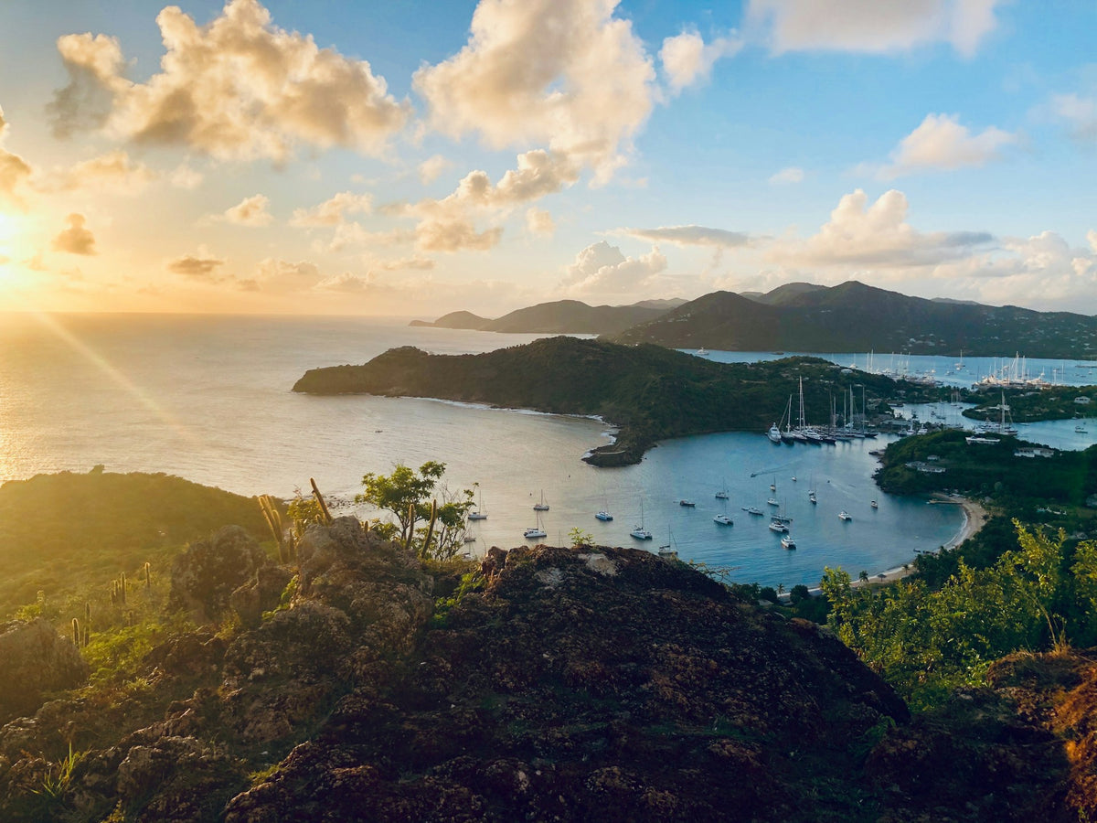 Scenic view of a coastal area with mountains and boats at sunset in Antigua and Barbuda.