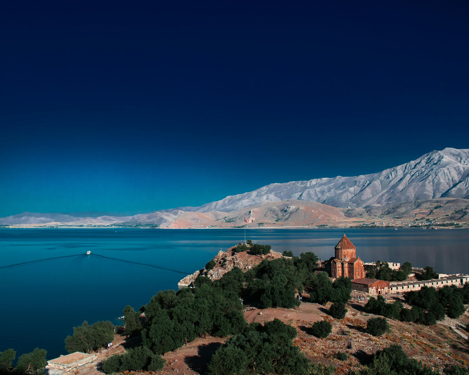 Historic building looking out on a lake in Armenia with mountains and blue sky in the background