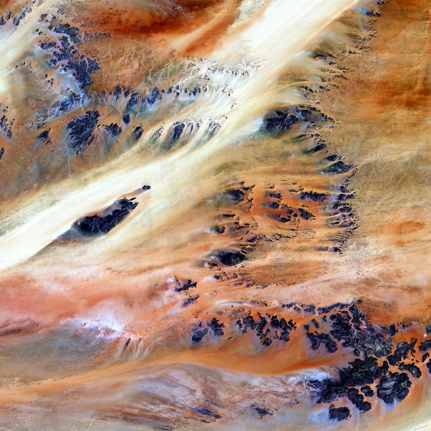 Aerial view of a desert landscape in Chad with sand dunes and rock formations.