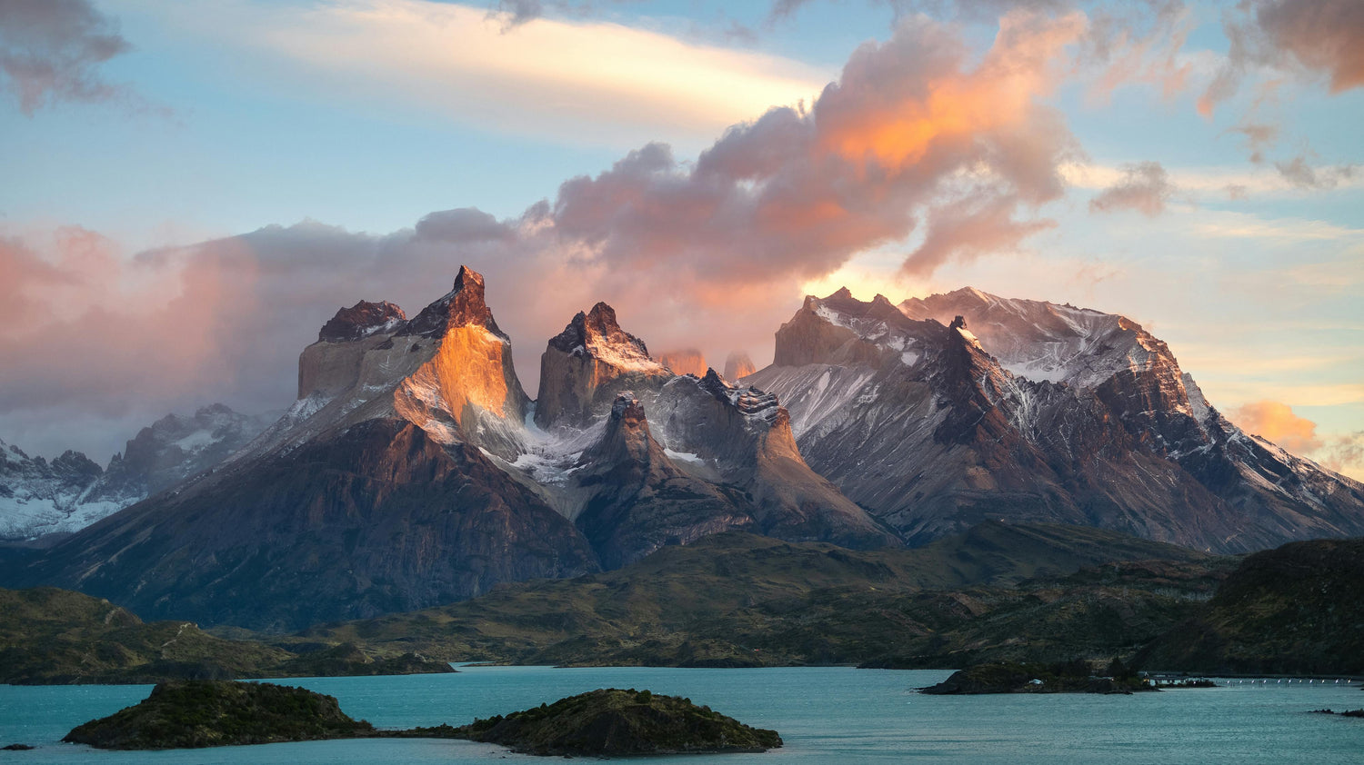 Mountain landscape in Chile with a lake and sunset, featuring snow-capped peaks and a colourful sky.