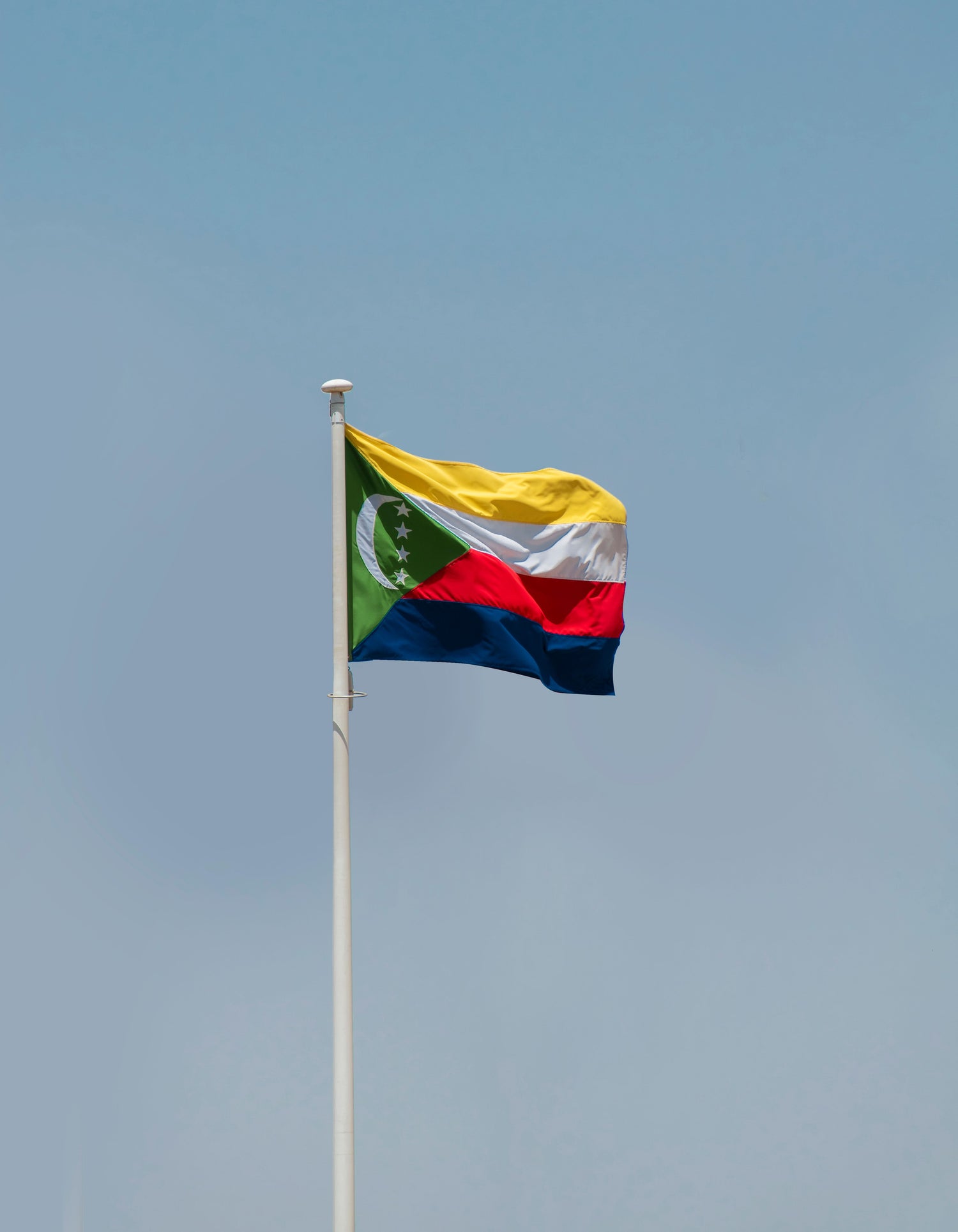 Flag of Comoros waving against a clear blue sky