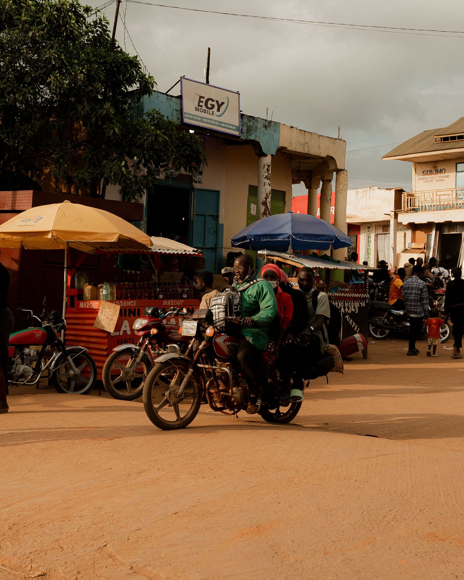 Motorcycle ride on a dirt road in Congo with people and shops in the background