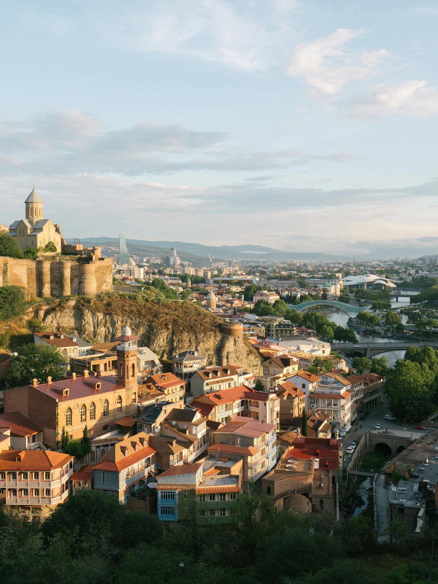 Picture of Georgia featuring houses, a mountainous castle, and river with bridges in the background