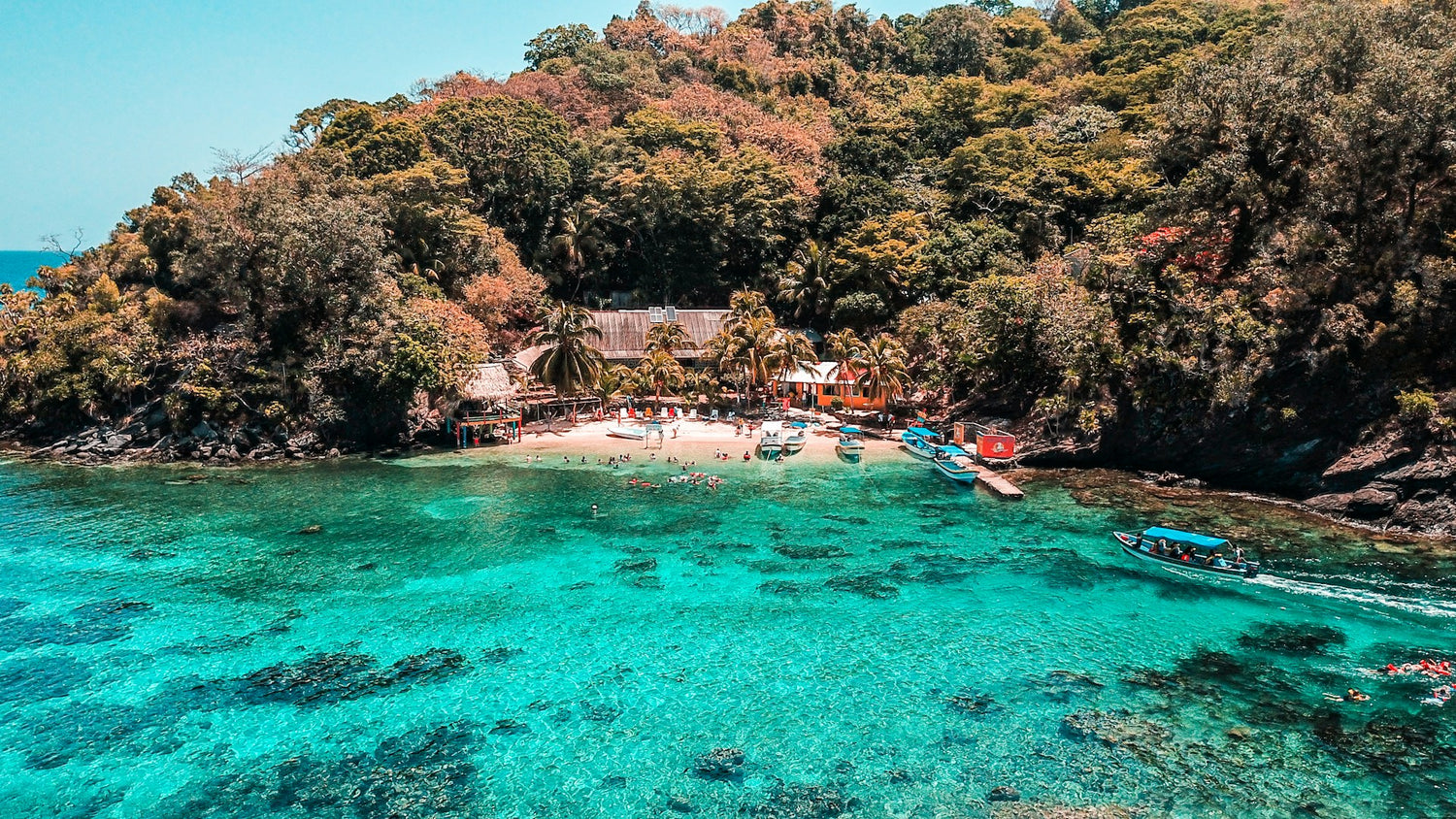 Tropical coast of Honduras with clear turquoise waters and a small dock.
