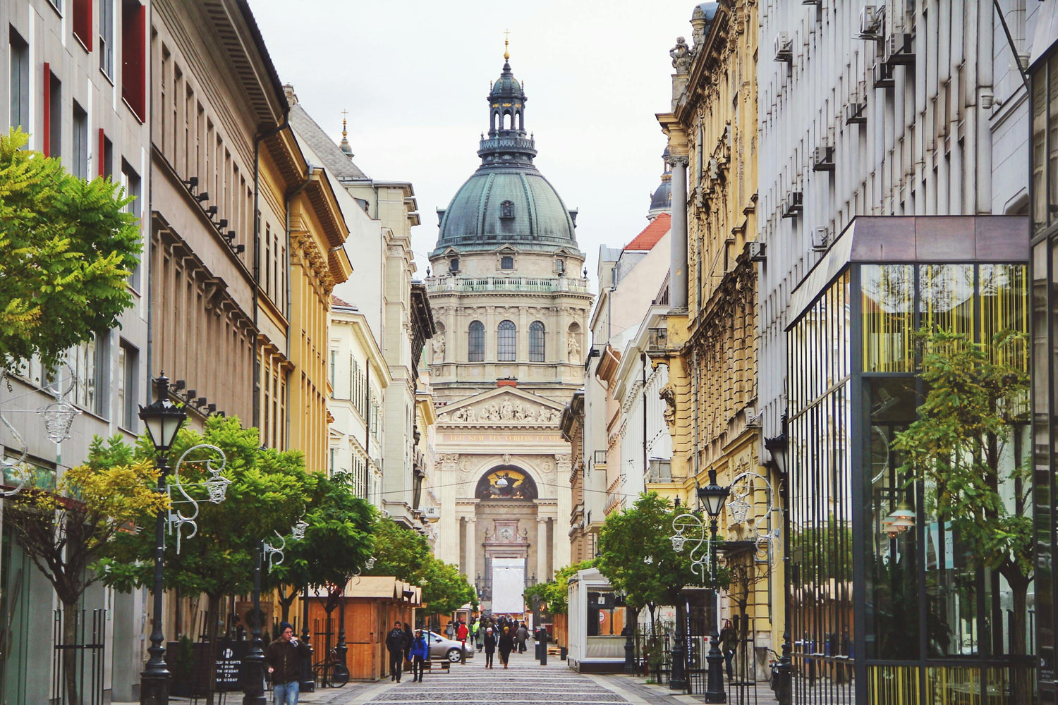 City street in Hungary featuring old buildings, greenery and St. Stephen's Basilica in the centre