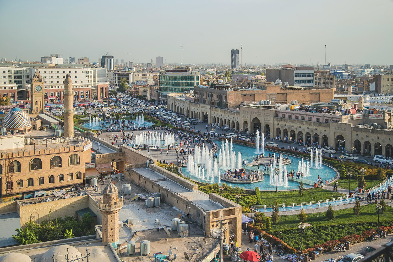 Picture of Iraq featuring a garden with fountains, surrounded by buildings and many cars