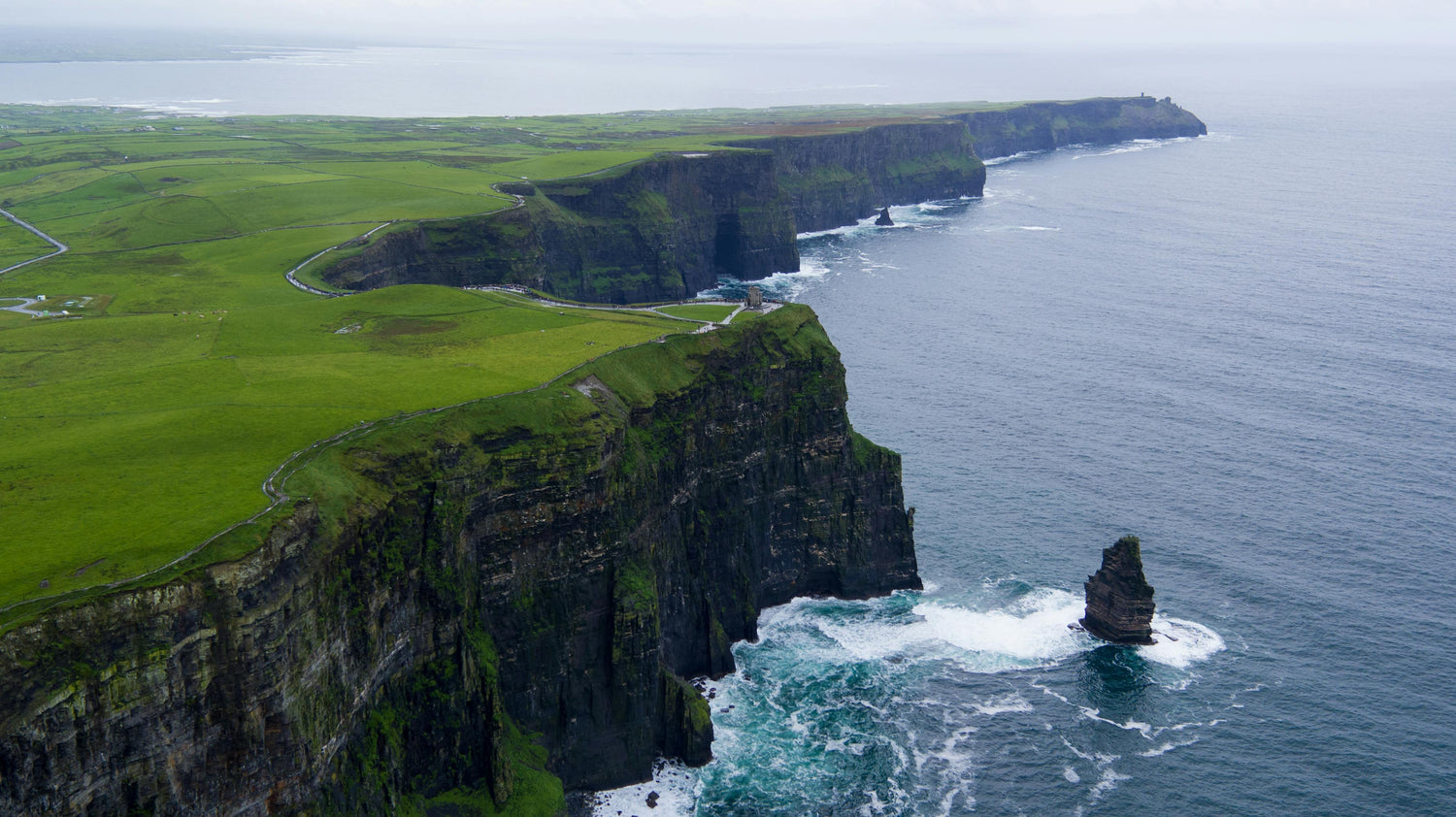 Cliffs of Moher in Ireland with the ocean to the right and a green landscape to the left.