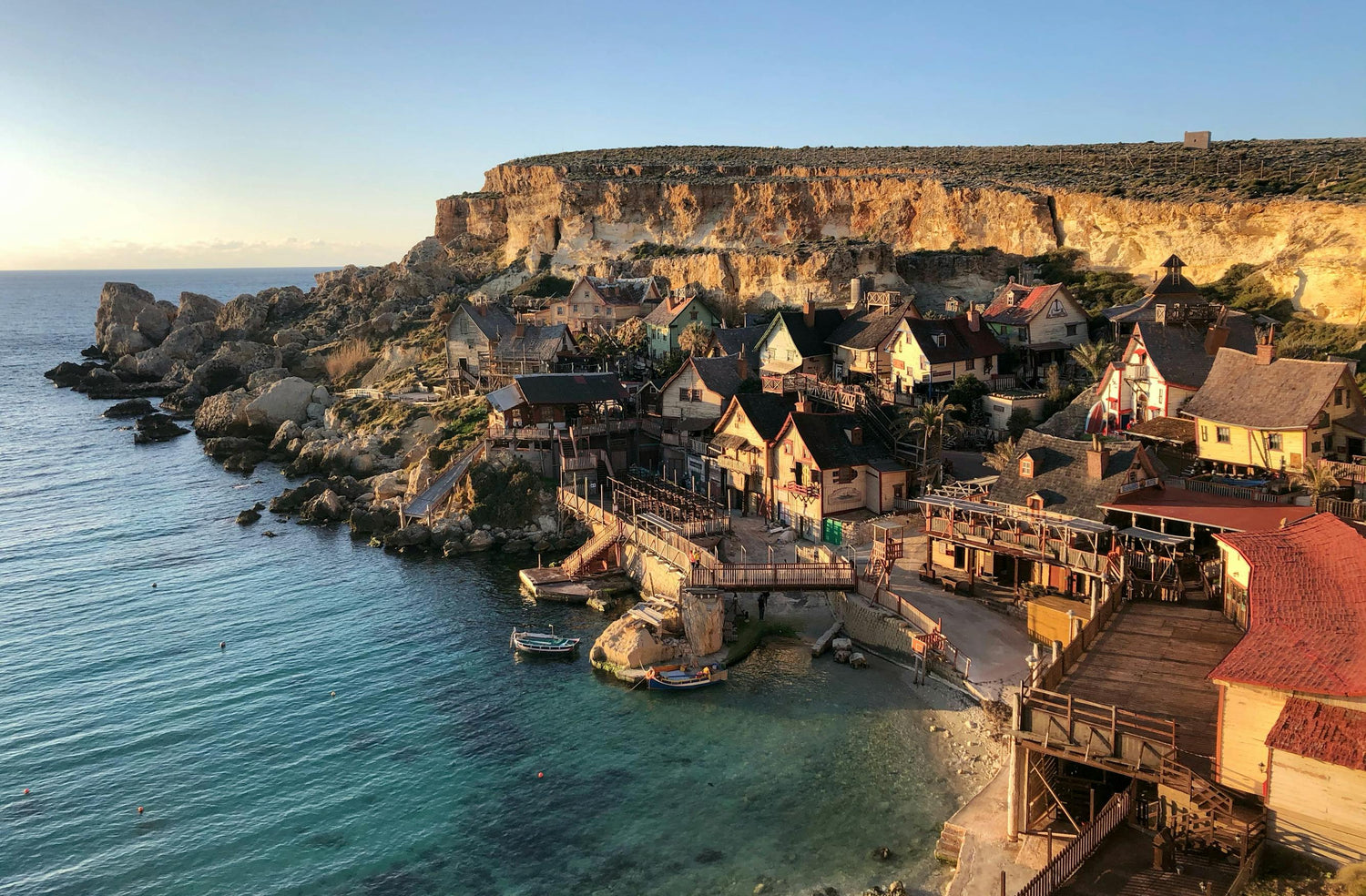 Coastal village in Malta with houses built into a cliffside overlooking the ocean.