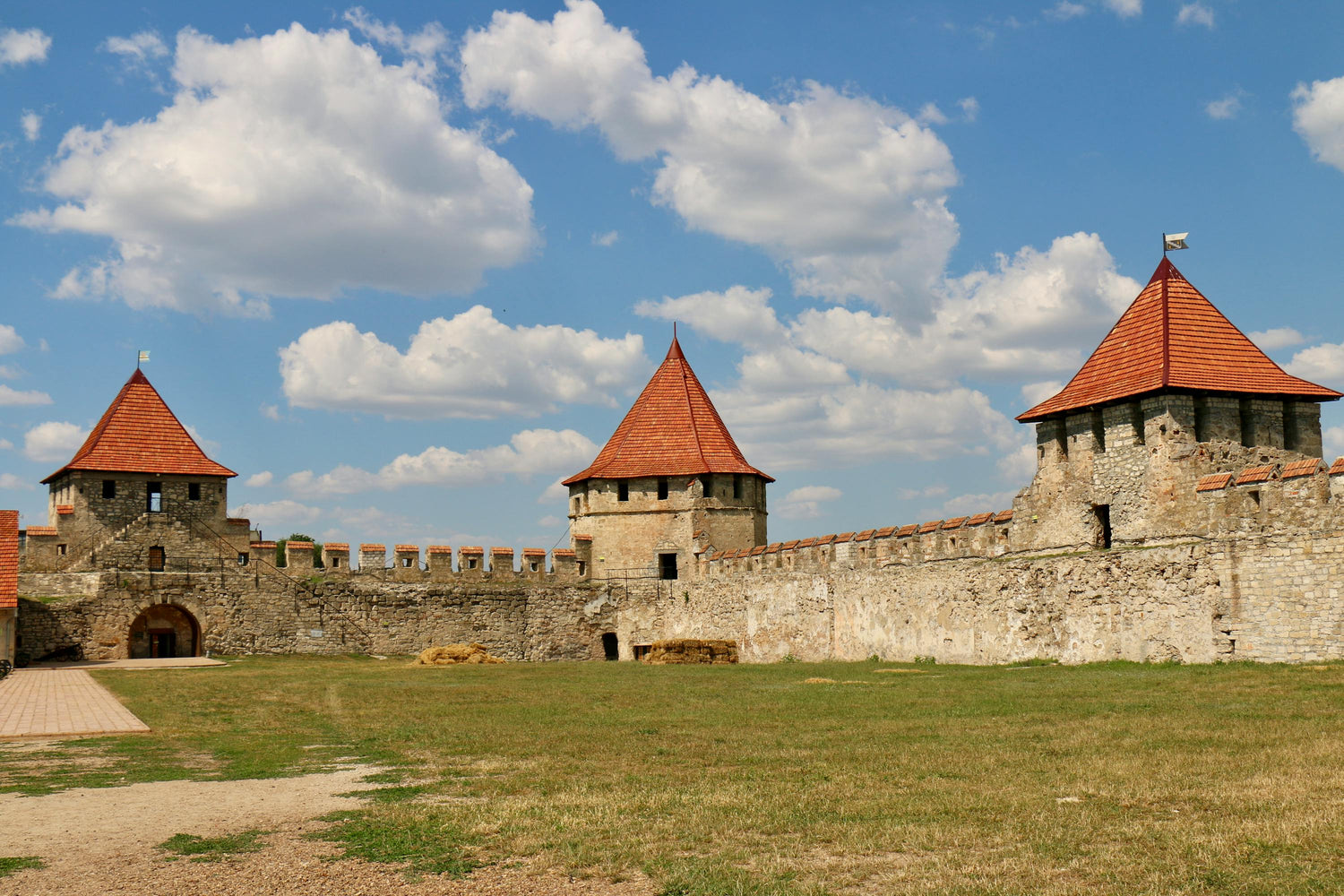 Stone fortress in Moldova with red-tiled towers under a blue sky with clouds
