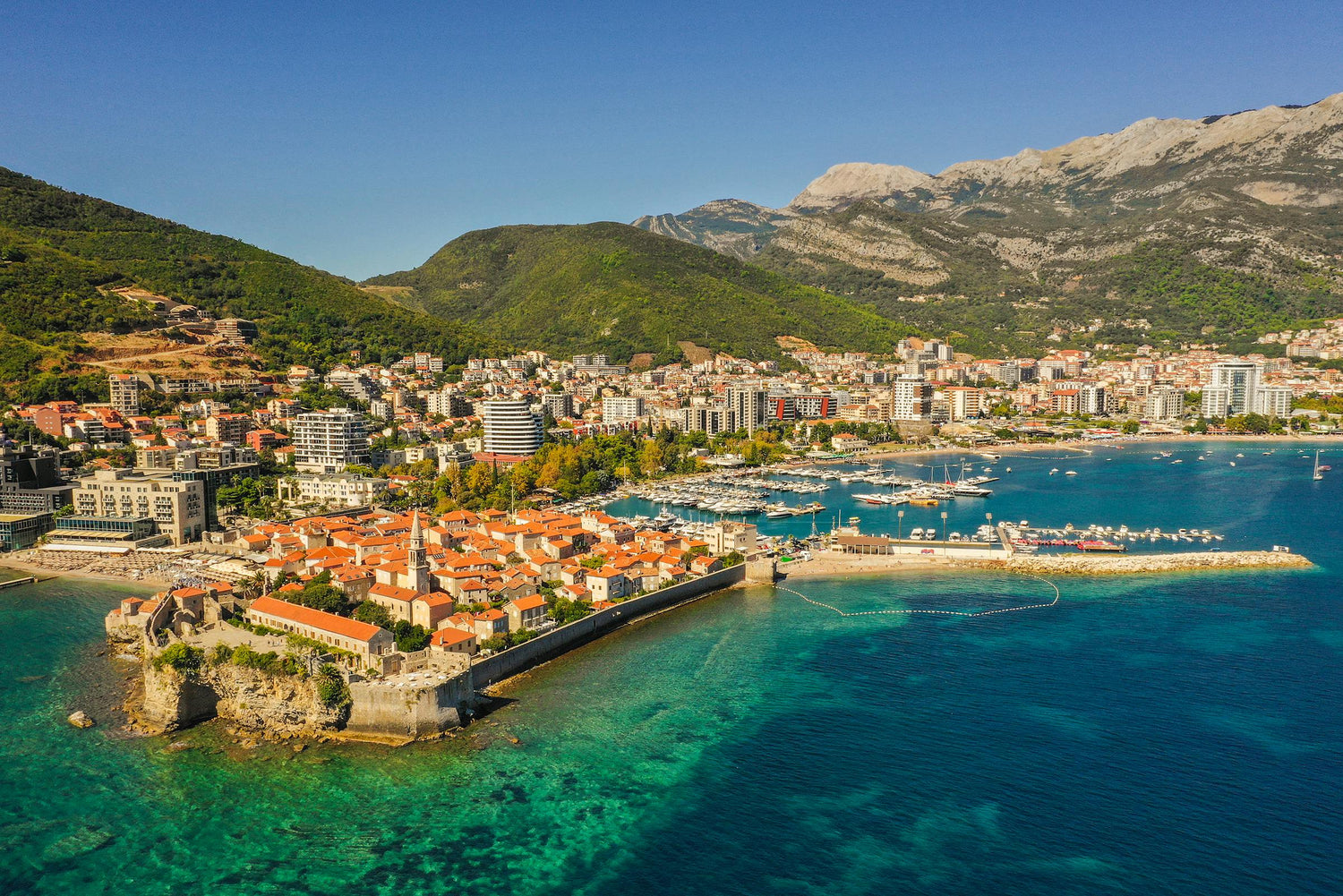 Coastal cityscape of Montenegro with mountains, buildings and clear blue water 