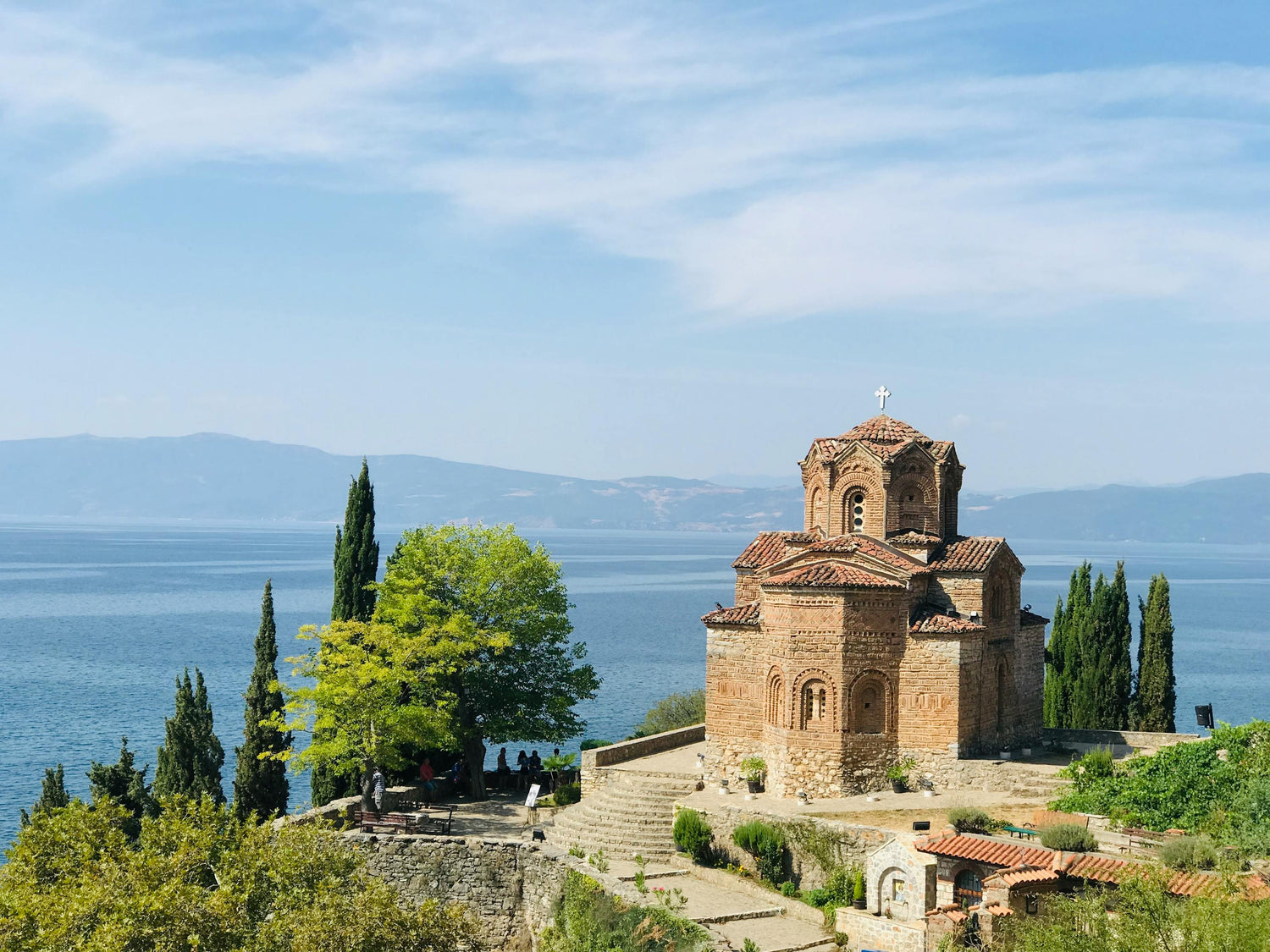St. John Kaneo Church on the shore of Lake Ohrid in North Macedonia with trees and steps leading up to it.