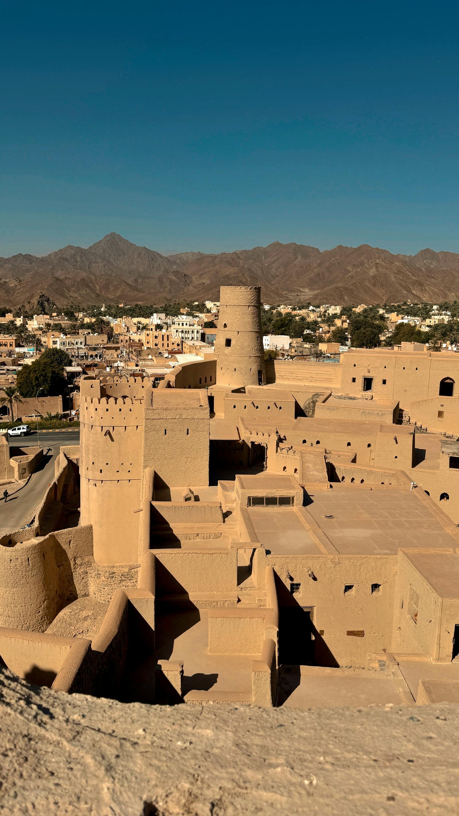 Traditional desert architecture of Oman with a clear blue sky and mountains in the background