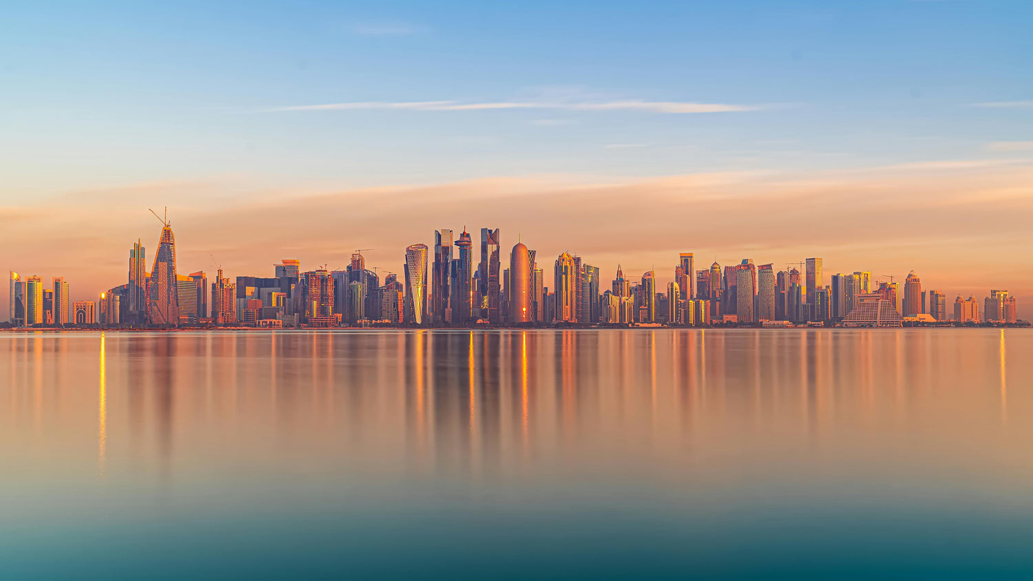 City skyline in Qatar at sunset with reflections on the water