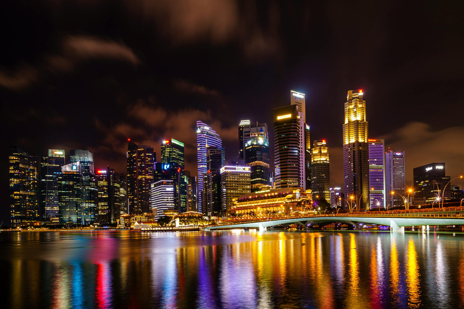 City skyline of Singapore at night with illuminated buildings reflected in water
