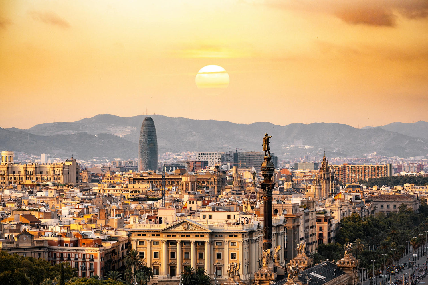 Cityscape of Barcelona with famous landmarks against a sunset sky.