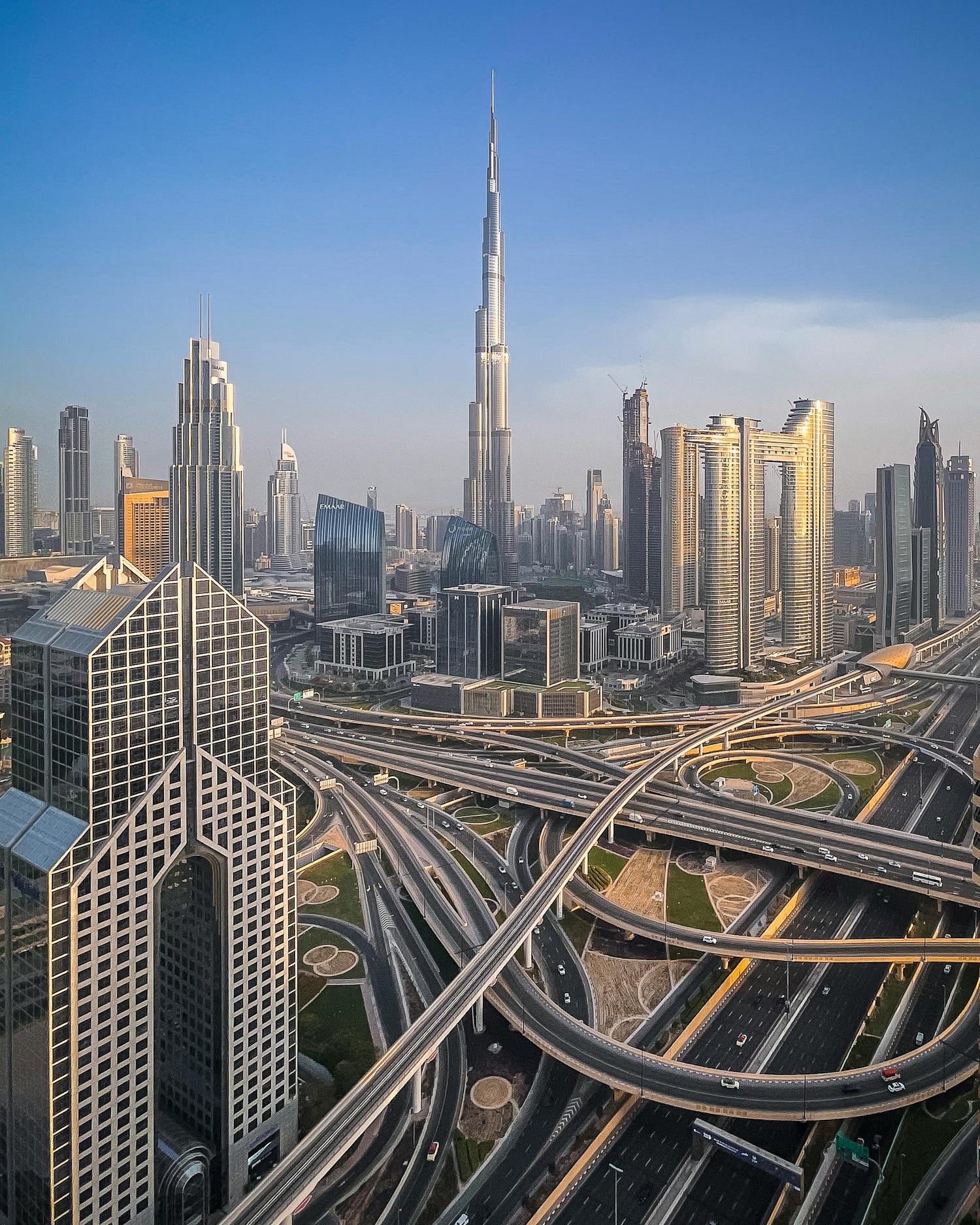 Aerial cityscape view with modern skyscrapers and a complex network of highways.