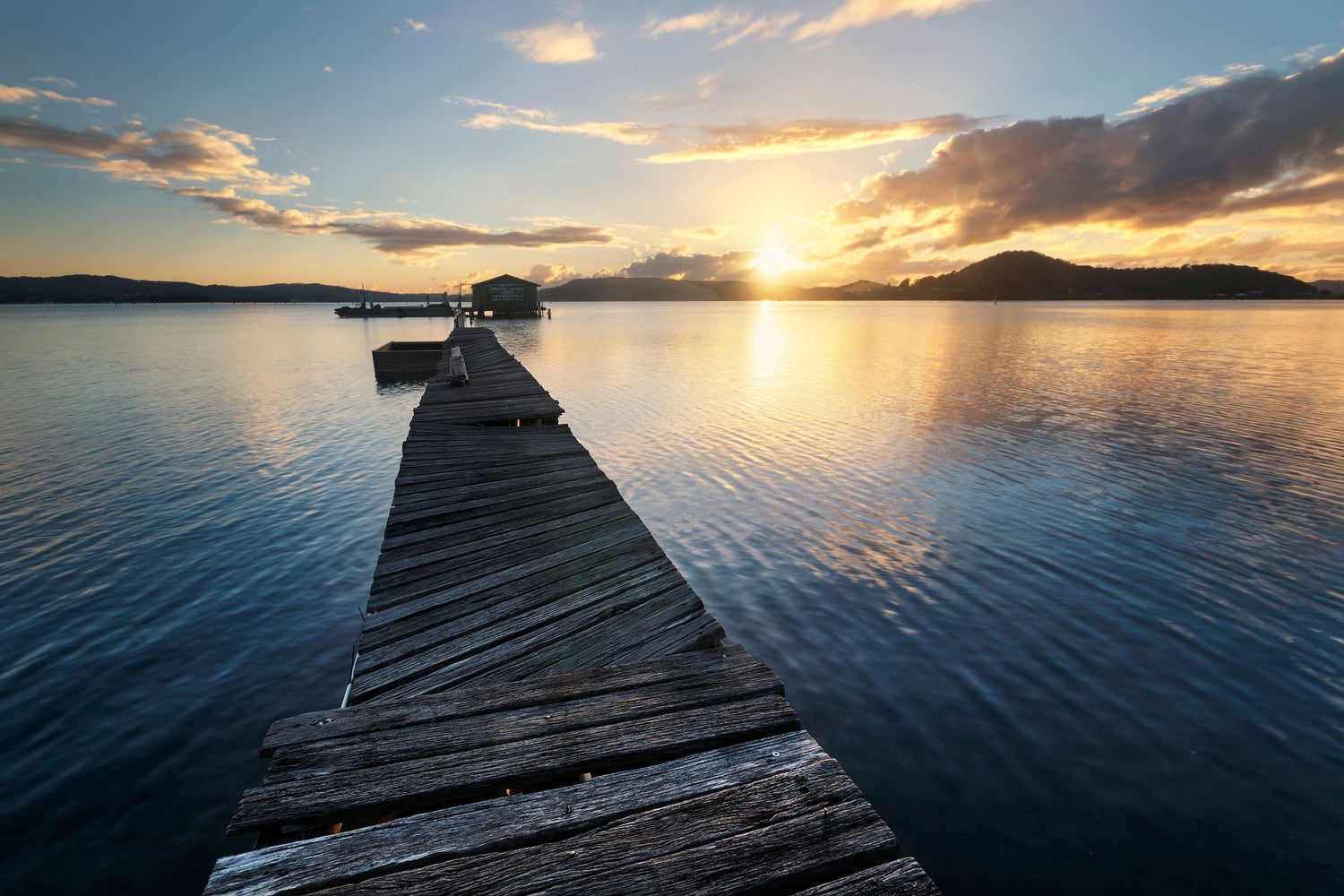 A wooden jetty on a beach at sunrise with a cloudy sky in the background, Tascott, NSW Central Coast, Australia.