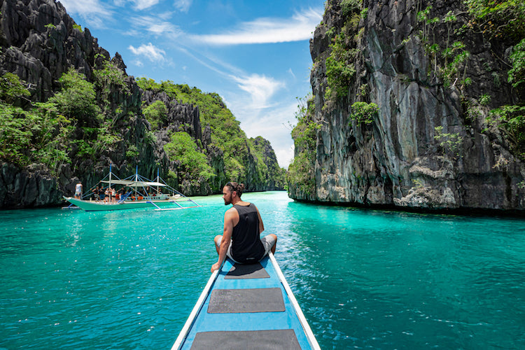 A solo traveller on the prow of a boat in the Philippines.