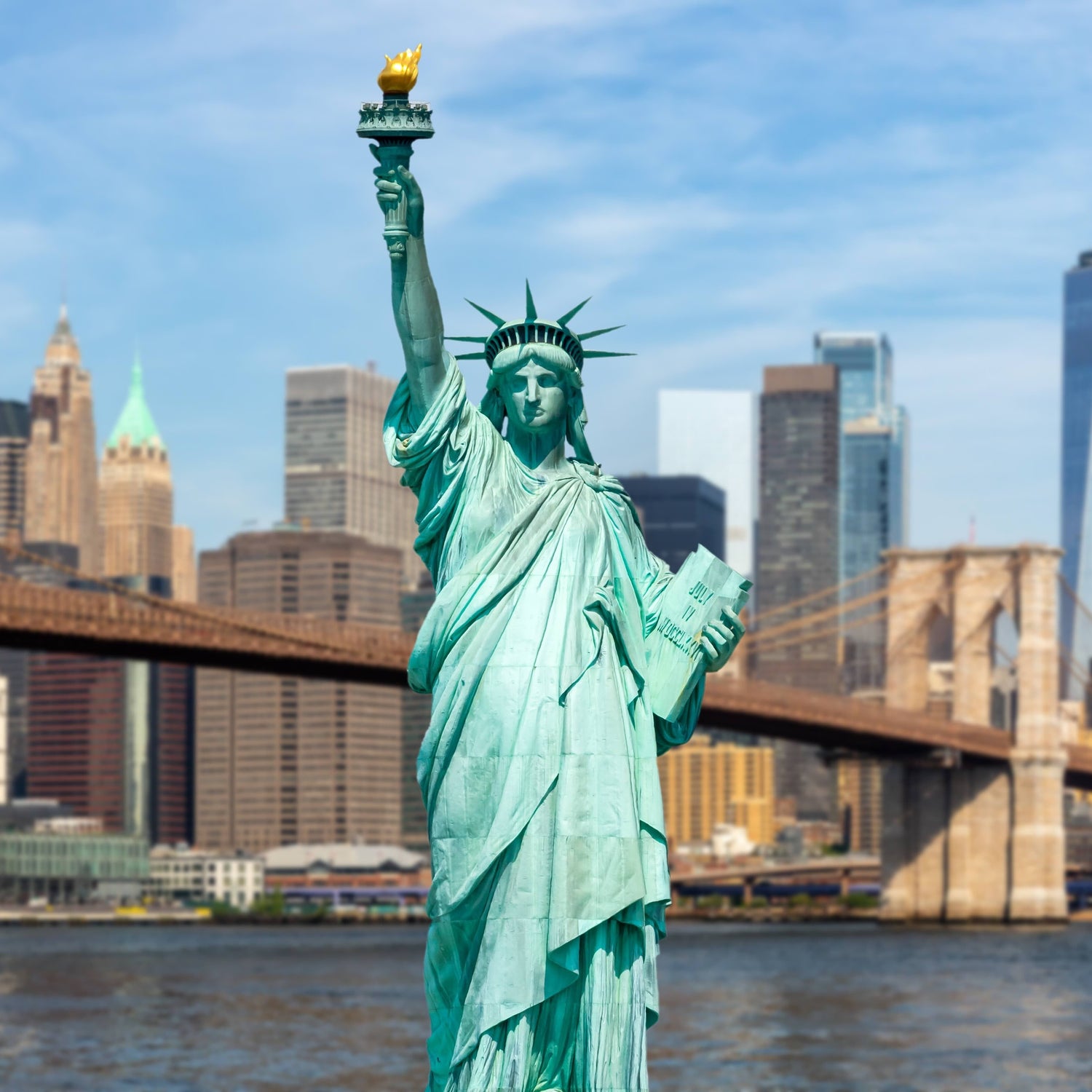 New York City skyline of Manhattan with Statue of Liberty and Brooklyn Bridge.
