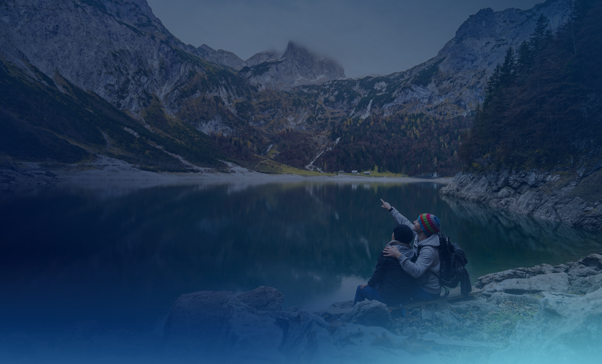 Two travellers at a lake in the mountains